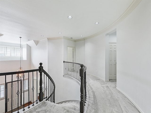 hallway featuring ornamental molding, an inviting chandelier, and light colored carpet