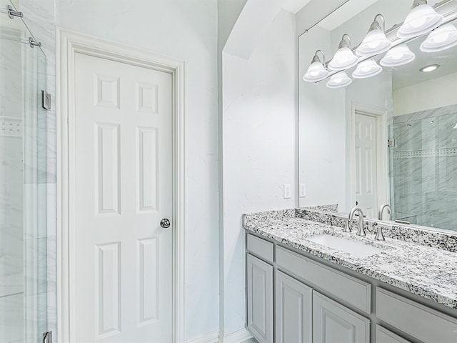 bathroom featuring a shower with door and vanity