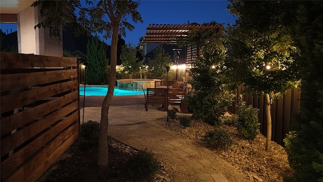 pool at night with a pergola and a patio area