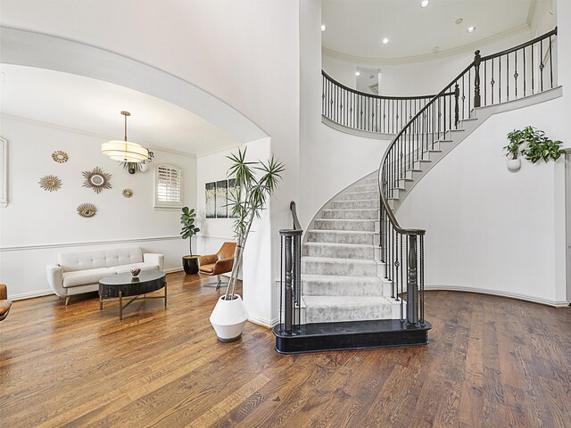 stairway with ornamental molding, hardwood / wood-style flooring, and a notable chandelier