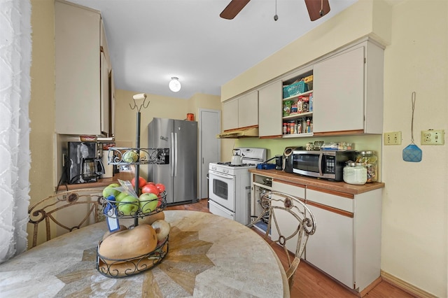 kitchen featuring light hardwood / wood-style flooring, appliances with stainless steel finishes, white cabinetry, wooden counters, and ceiling fan