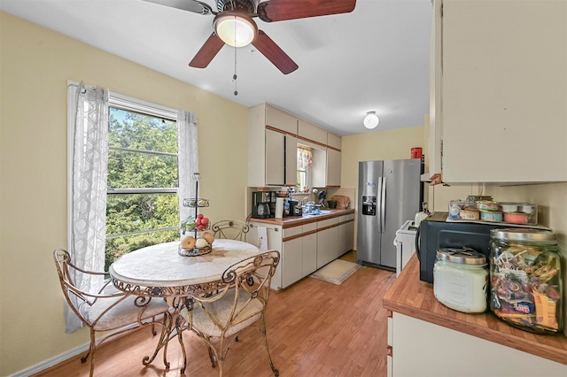 kitchen featuring stainless steel fridge, light hardwood / wood-style flooring, ceiling fan, white cabinetry, and wooden counters