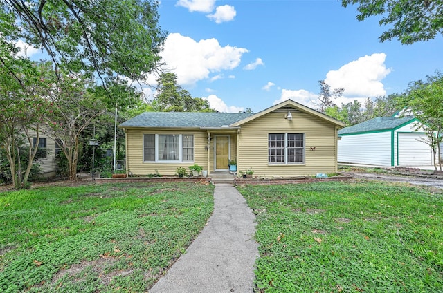 ranch-style home with a garage, an outdoor structure, and a front yard