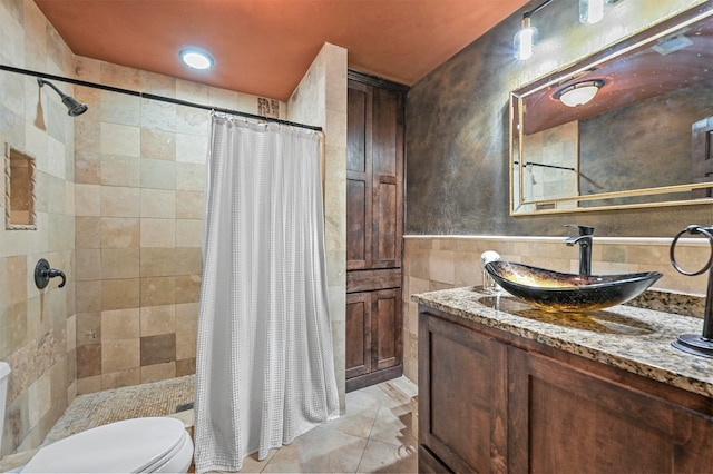 bathroom with tile patterned floors, walk in shower, toilet, tile walls, and vanity