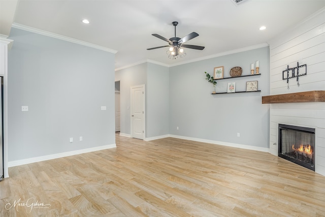 unfurnished living room with crown molding, a large fireplace, ceiling fan, and light hardwood / wood-style flooring