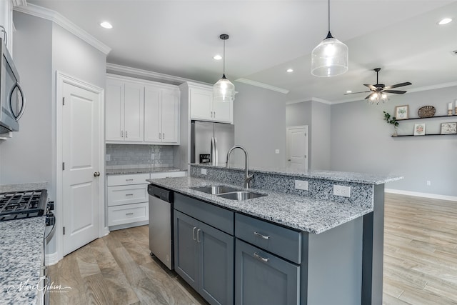 kitchen with appliances with stainless steel finishes, crown molding, sink, white cabinetry, and ceiling fan