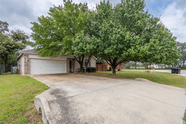 view of property hidden behind natural elements with a garage and a front yard