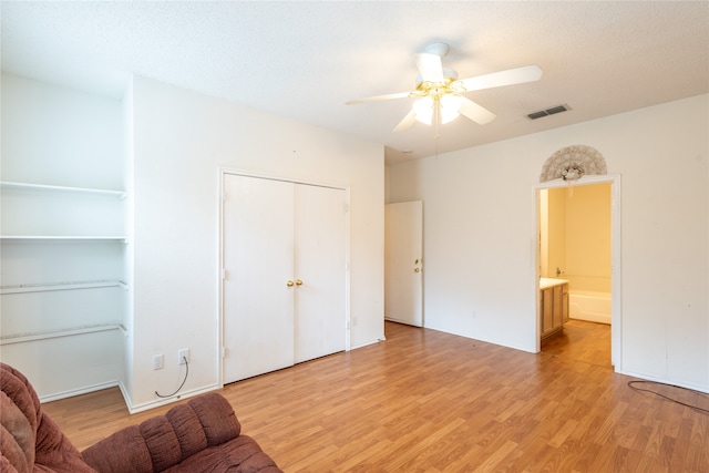 living room with light wood-type flooring, a textured ceiling, and ceiling fan