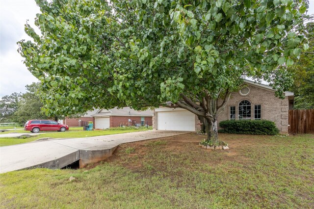 view of property hidden behind natural elements featuring a garage and a front lawn