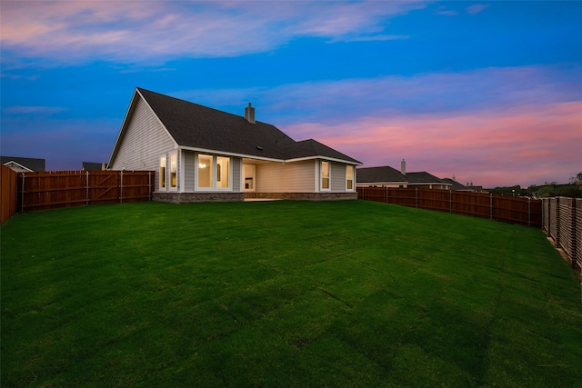 back house at dusk featuring a patio and a yard