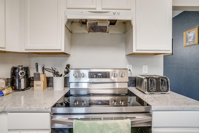 kitchen with stainless steel range with electric cooktop, white cabinets, and light stone counters