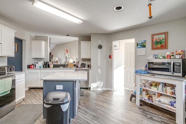 kitchen featuring white cabinets, a kitchen island, appliances with stainless steel finishes, and light hardwood / wood-style flooring