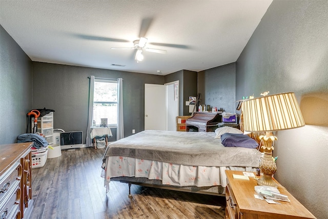 bedroom with a textured ceiling, ceiling fan, and dark wood-type flooring