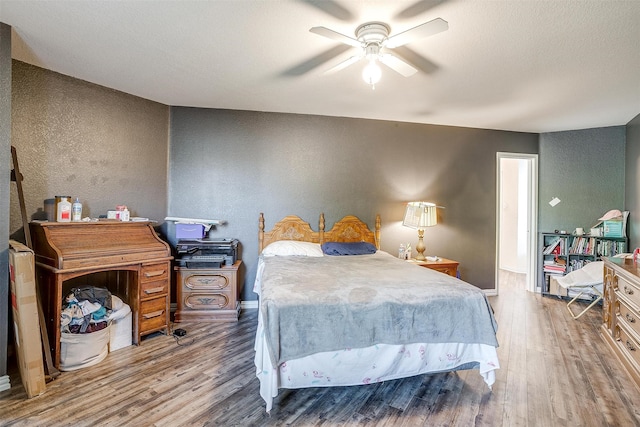 bedroom featuring ceiling fan, hardwood / wood-style flooring, and a textured ceiling