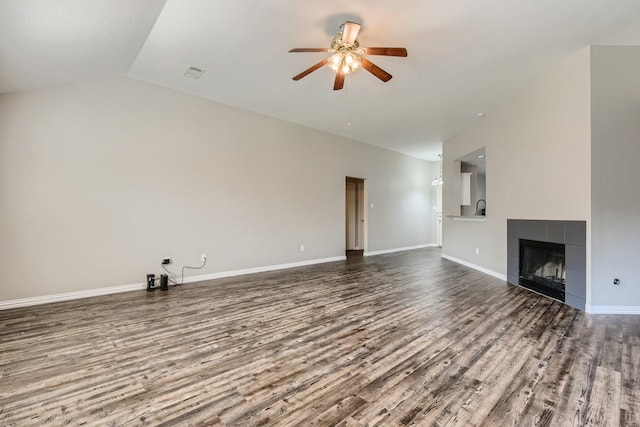 unfurnished living room with lofted ceiling, ceiling fan, a tile fireplace, and hardwood / wood-style flooring