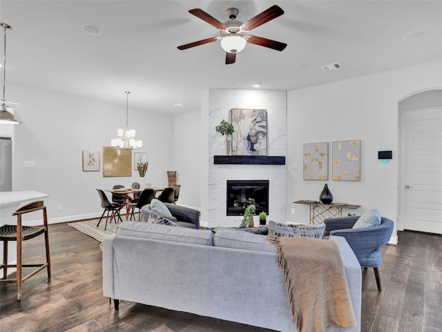 living room featuring dark hardwood / wood-style floors, a premium fireplace, and ceiling fan with notable chandelier