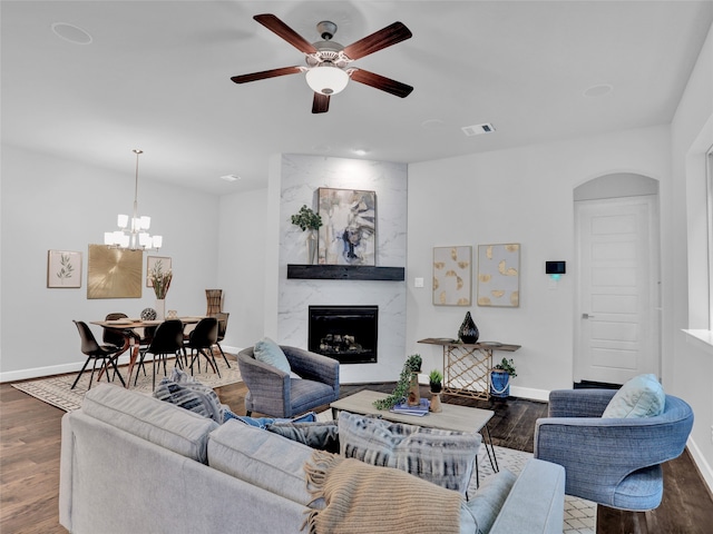 living room featuring ceiling fan with notable chandelier, dark wood-type flooring, and a high end fireplace