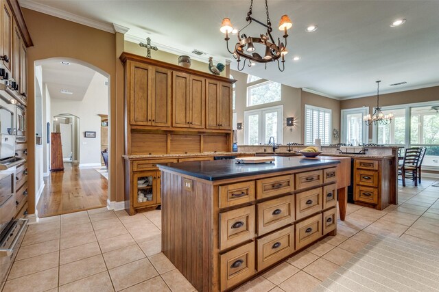 kitchen with ornamental molding, an inviting chandelier, a center island, and light tile patterned flooring