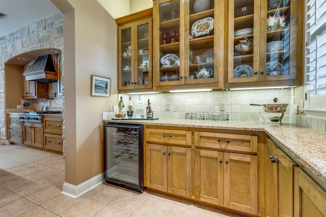 bar featuring light stone countertops, beverage cooler, backsplash, premium range hood, and light tile patterned flooring