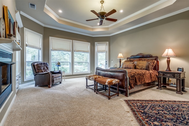 bedroom with crown molding, ceiling fan, light carpet, and a tray ceiling