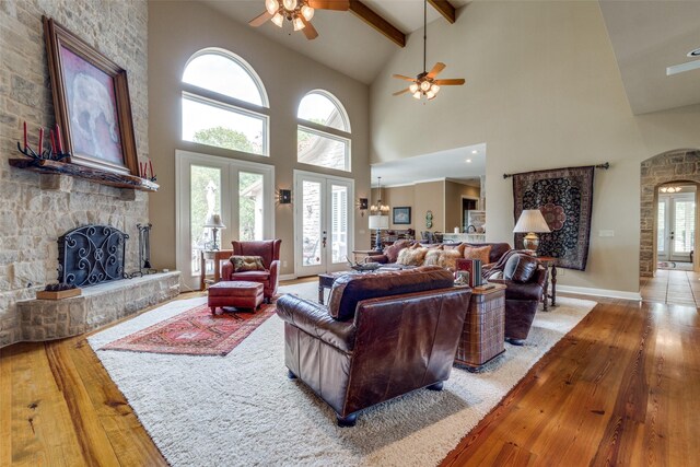 living room featuring a fireplace, wood-type flooring, beam ceiling, and ceiling fan