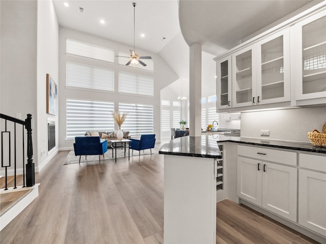 kitchen with light wood-type flooring, ceiling fan, high vaulted ceiling, and white cabinetry