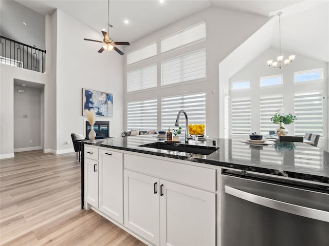 kitchen with white cabinets, light hardwood / wood-style flooring, ceiling fan with notable chandelier, sink, and high vaulted ceiling