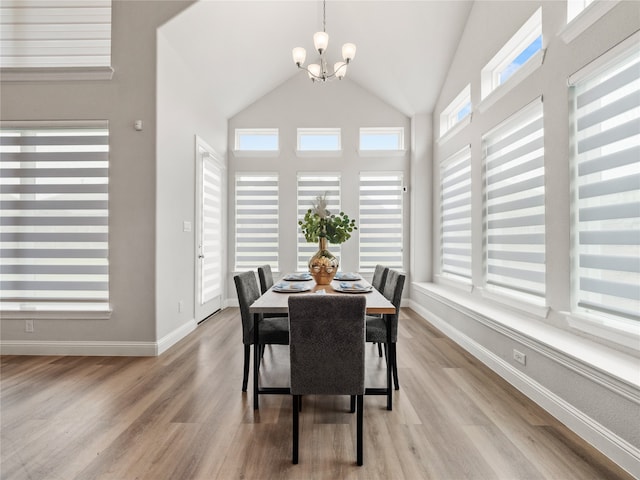 dining area featuring light hardwood / wood-style flooring, high vaulted ceiling, and a chandelier