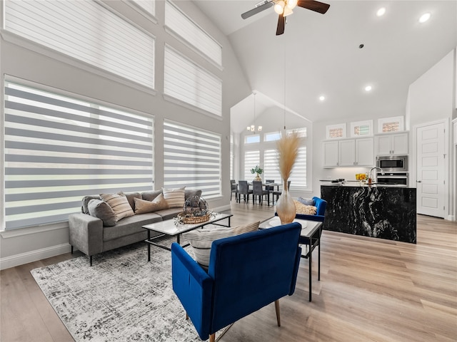 living room featuring high vaulted ceiling, ceiling fan, and light hardwood / wood-style floors