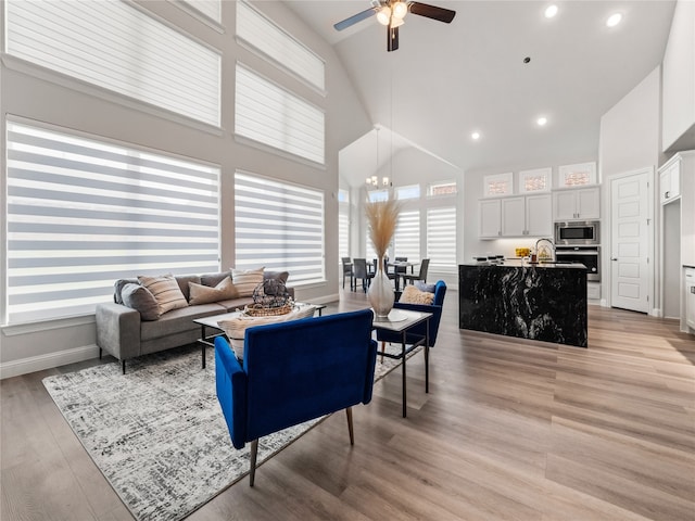 living room with high vaulted ceiling, sink, ceiling fan, and light hardwood / wood-style floors