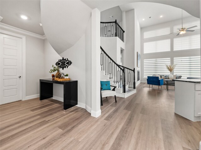 interior space with crown molding, a towering ceiling, hardwood / wood-style flooring, and ceiling fan