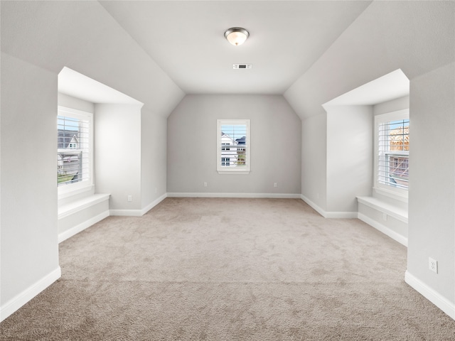 bonus room featuring lofted ceiling, light carpet, and a healthy amount of sunlight