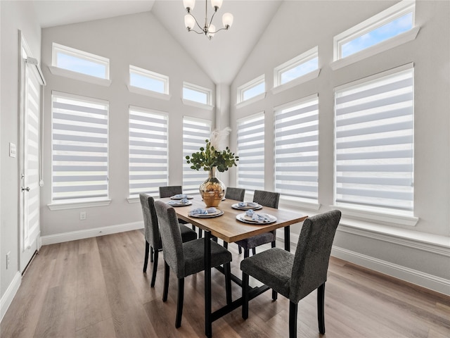 dining area featuring high vaulted ceiling, light hardwood / wood-style flooring, and a notable chandelier