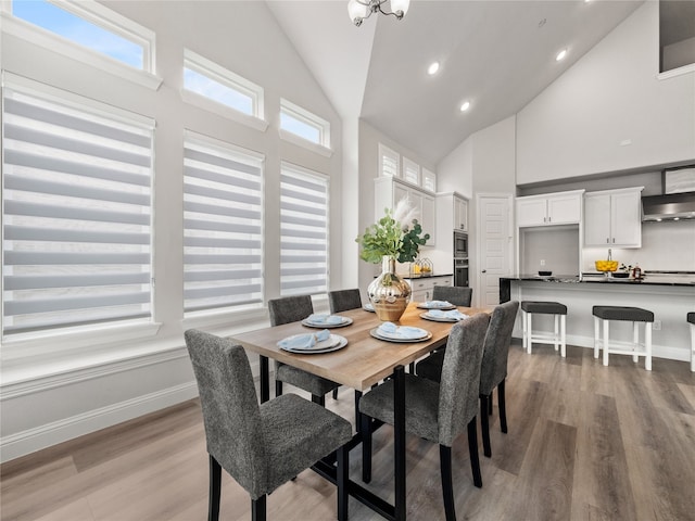 dining area featuring light wood-type flooring and high vaulted ceiling