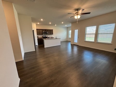 unfurnished living room with dark hardwood / wood-style flooring and ceiling fan