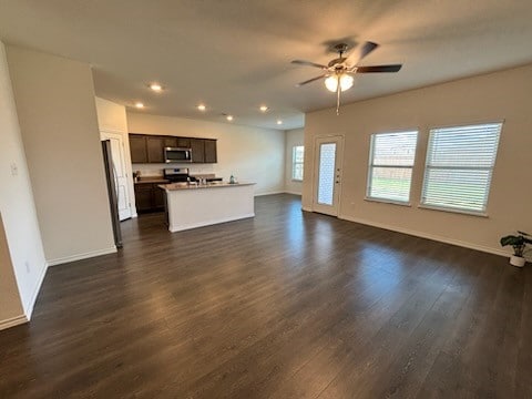 unfurnished living room with dark hardwood / wood-style flooring and ceiling fan