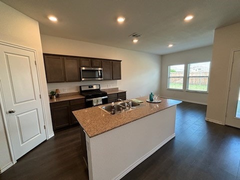 kitchen with dark wood-type flooring, sink, a kitchen island with sink, and stainless steel appliances