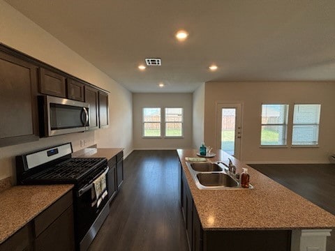 kitchen featuring stainless steel appliances, sink, an island with sink, dark hardwood / wood-style floors, and dark brown cabinets