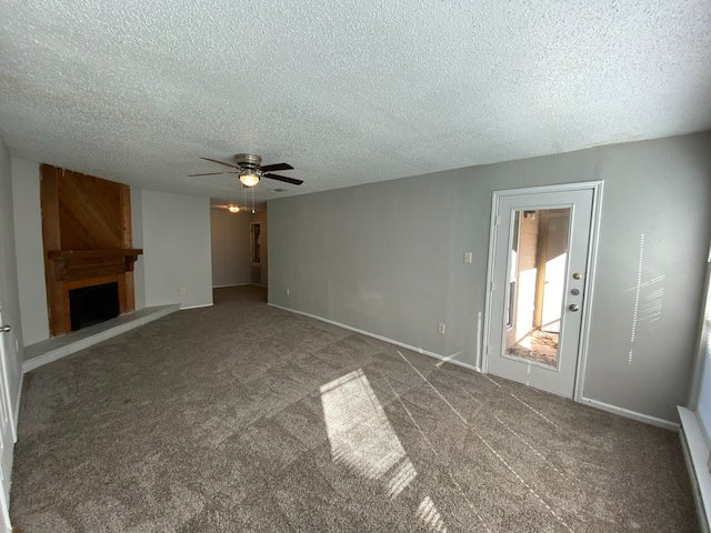 unfurnished living room with a textured ceiling, a large fireplace, ceiling fan, and carpet floors