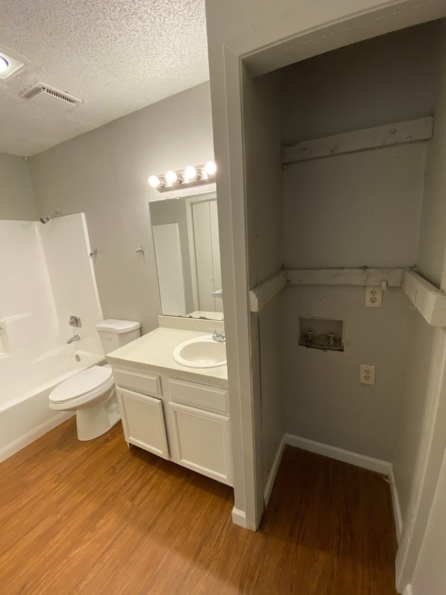 full bathroom with toilet, hardwood / wood-style floors, vanity, a textured ceiling, and tub / shower combination