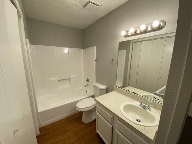 full bathroom featuring bathtub / shower combination, toilet, wood-type flooring, vanity, and a textured ceiling