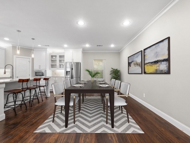 dining space featuring ornamental molding, dark hardwood / wood-style flooring, and sink