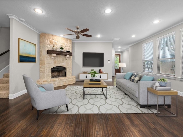 living room with a fireplace, crown molding, hardwood / wood-style floors, ceiling fan, and a textured ceiling