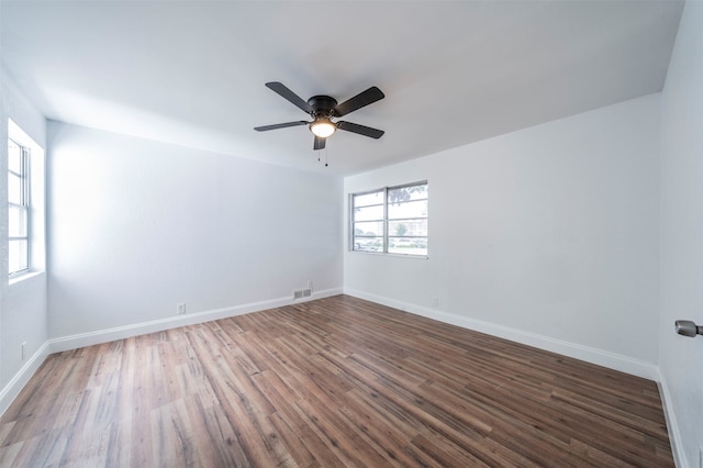 unfurnished room featuring dark wood-type flooring, a wealth of natural light, and ceiling fan