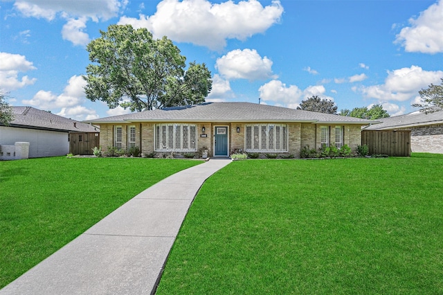 ranch-style home with brick siding, fence, and a front yard