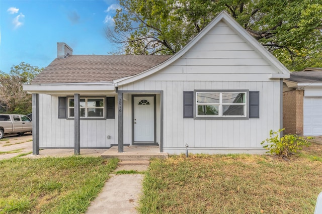 view of front facade featuring a front lawn, a garage, and covered porch