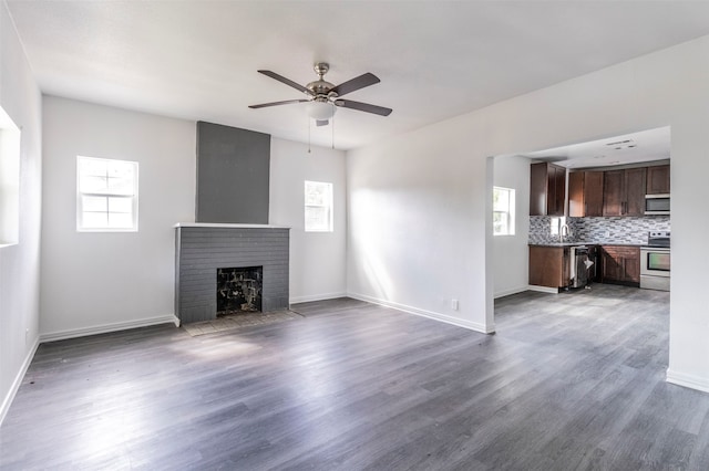 unfurnished living room with ceiling fan, sink, hardwood / wood-style flooring, and a fireplace