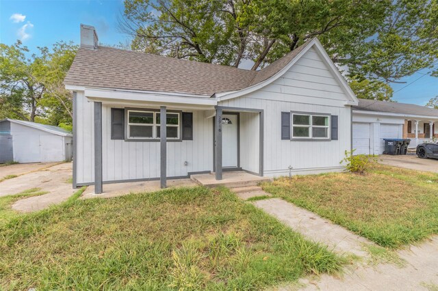 view of front of house with a garage, covered porch, and a front yard