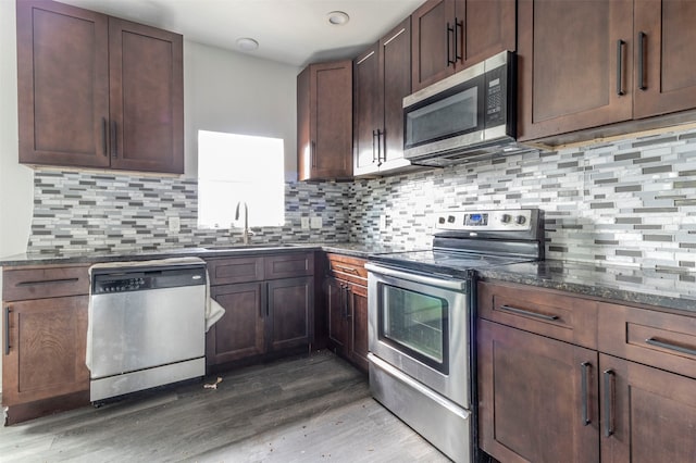 kitchen with backsplash, sink, hardwood / wood-style floors, and appliances with stainless steel finishes