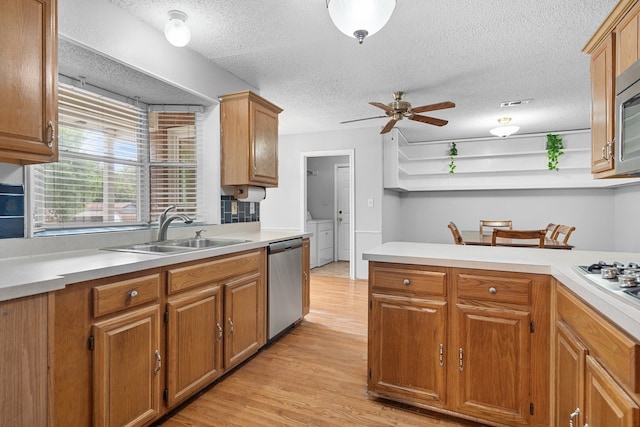 kitchen with washer and clothes dryer, light hardwood / wood-style flooring, sink, ceiling fan, and stainless steel dishwasher